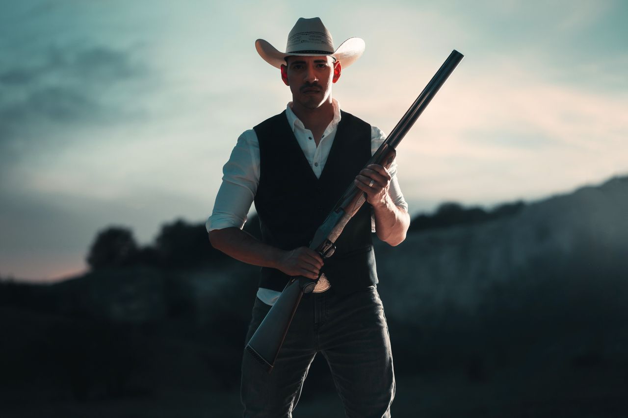 The Art of Drawing Readers In: Your attractive post title goes here A cowboy in traditional attire holding a shotgun, standing outdoors in San Antonio, Texas.