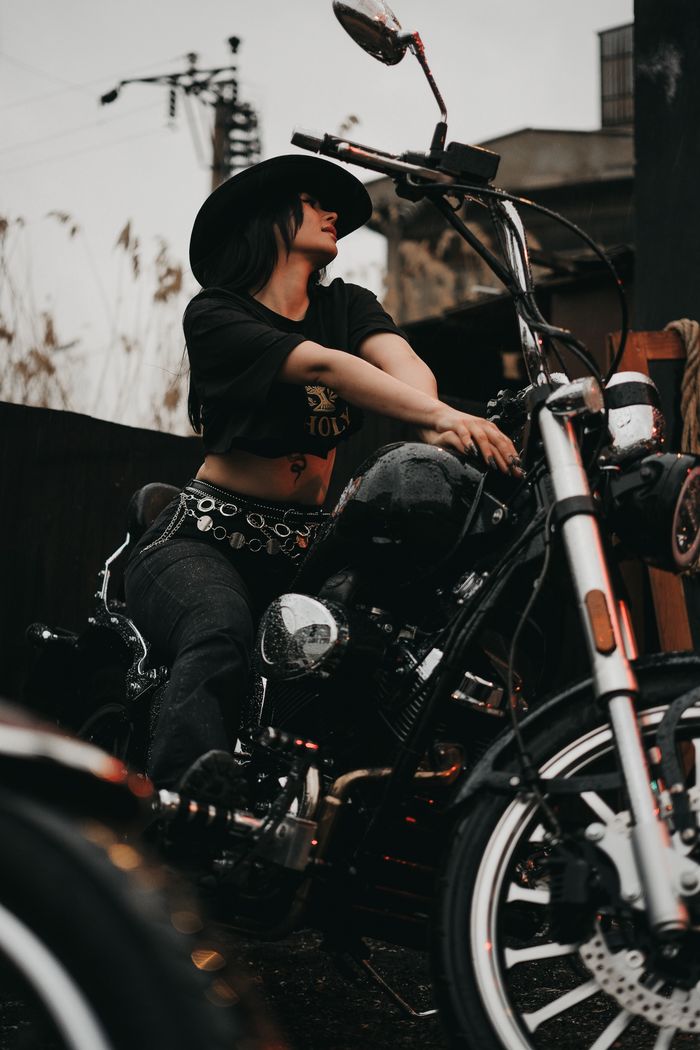 Crafting Captivating Headlines: Your awesome post title goes here A woman wearing a hat poses confidently on a motorcycle, captured in an outdoor, urban setting.